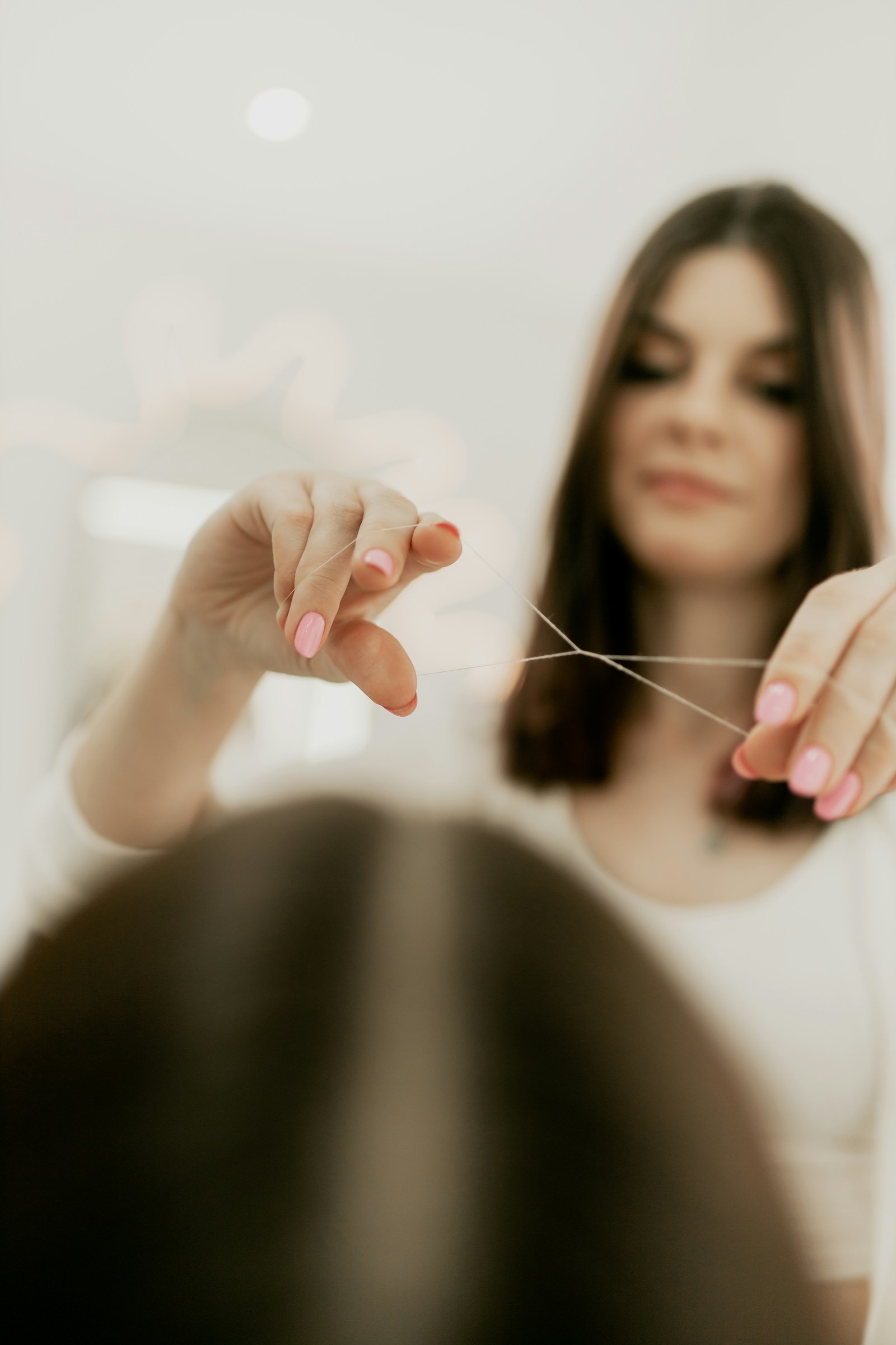 Threading a client's brow with cotton thread in a bright white salon